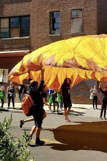 Group of people lifting a sunflower-shaped parachute in the air together